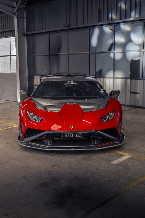 Red Lamborghini Huracan STO head-on inside a dark warehouse