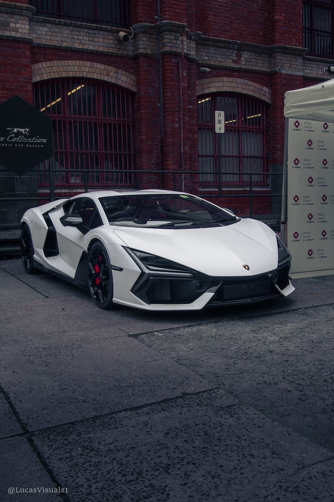 White Lamborghini Revuelto in front of a brick warehouse