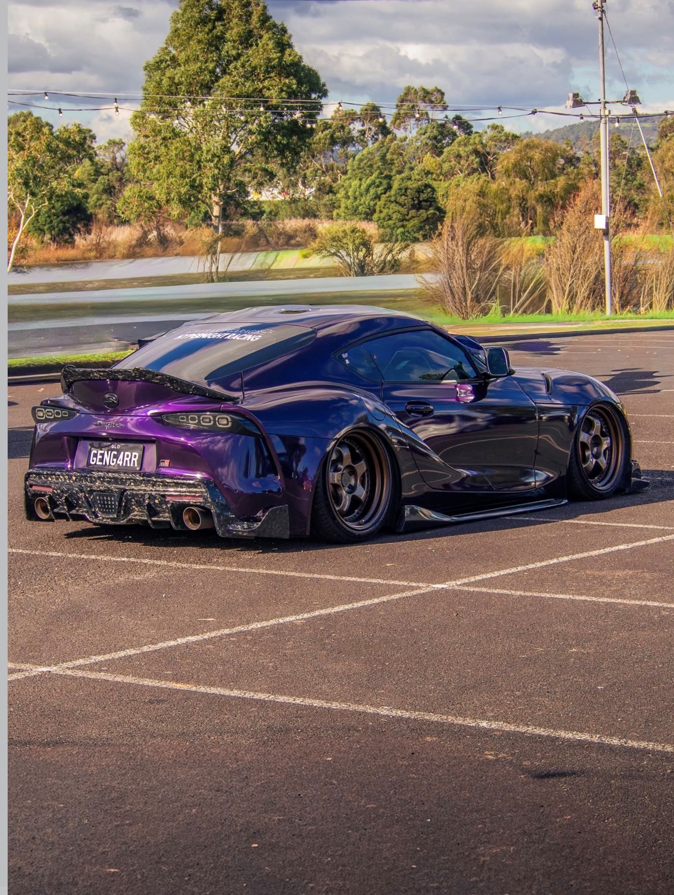 Purple widebody Toyota Supra parked in an empty car park at golden hour