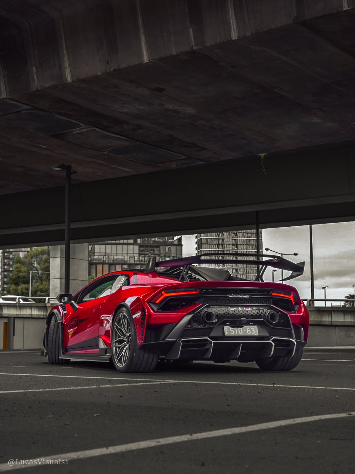 Red Ferrari parked under a concrete underpass